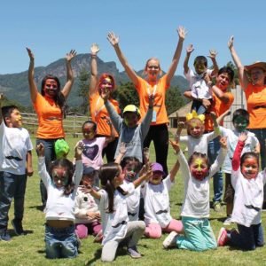 Volunteers and children with painted faces enjoying outdoor activities at a summer camp in Tlatlauquitepec, Puebla, Mexico.