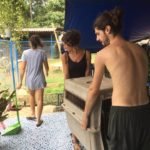 Young volunteers at Happy Dogs Koh Chang in Thailand lifting a large dog crate during daily care tasks at the dog rescue shelter.