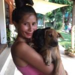 Smiling volunteer at Happy Dogs Koh Chang in Thailand holding two rescue puppies at the dog shelter.