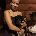 Woman holding a rescue dog on her lap at Happy Dogs Koh Chang, a dog shelter in Thailand, with a child sitting beside her.
