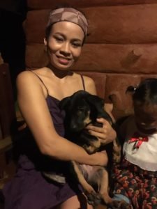 Woman holding a rescue dog on her lap at Happy Dogs Koh Chang, a dog shelter in Thailand, with a child sitting beside her.