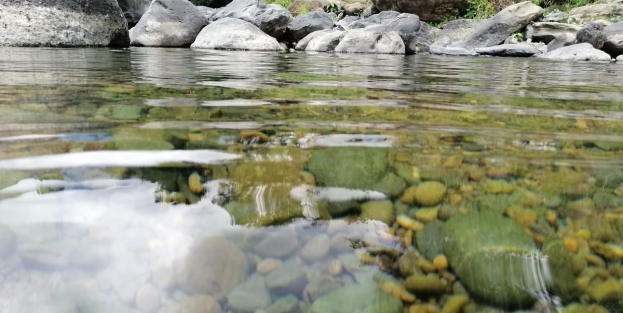 Shallow clear river with rocks and forested banks near a rural mountain farm in Dos Bocas, Costa Rica, part of a free food and accommodation farm volunteering project.