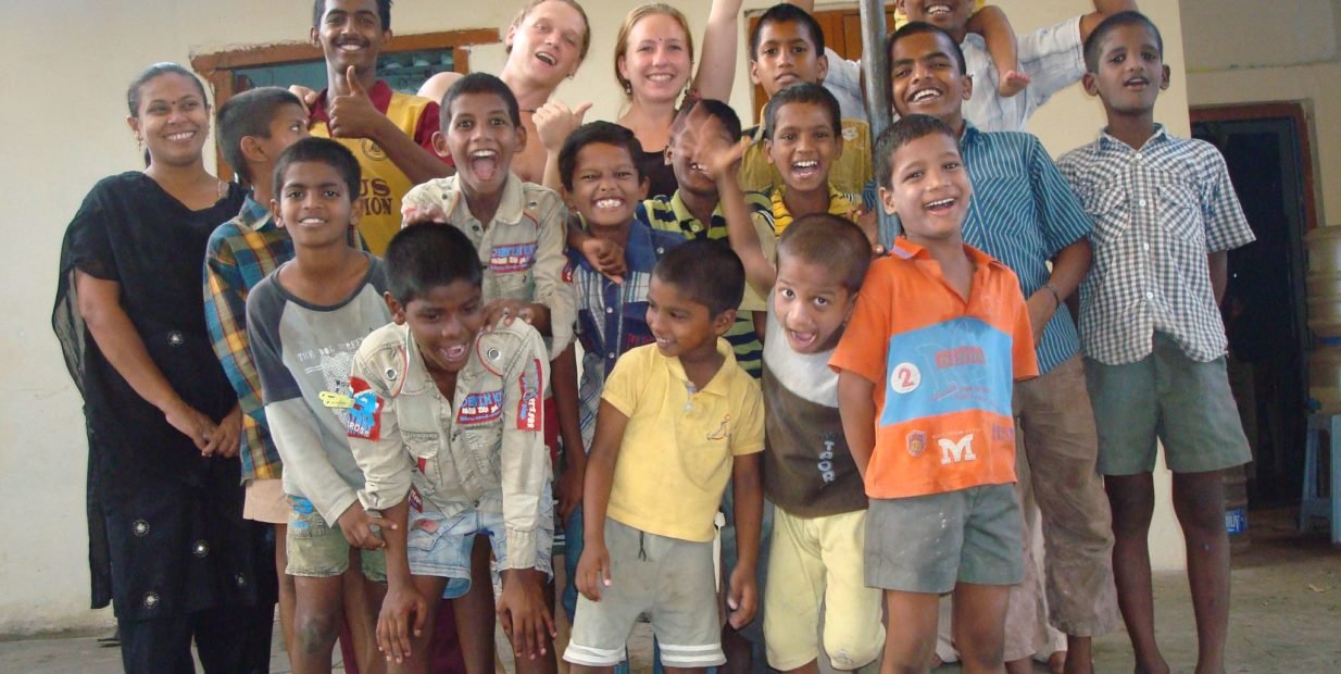 A group of children and volunteers smiling and posing together at a children’s home in Chennai, India.