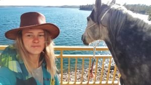 Horse travel Spain to France - Grace (Gražina) with her gray horse Currito by a lakeside railing in Spain during a long distance journey.