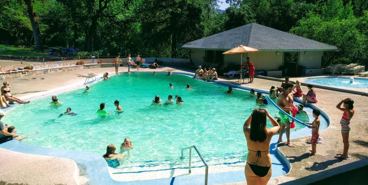 People swimming and relaxing in a natural geothermal spring pool at Aletheia Springs community in Sonoma Valley, California.
