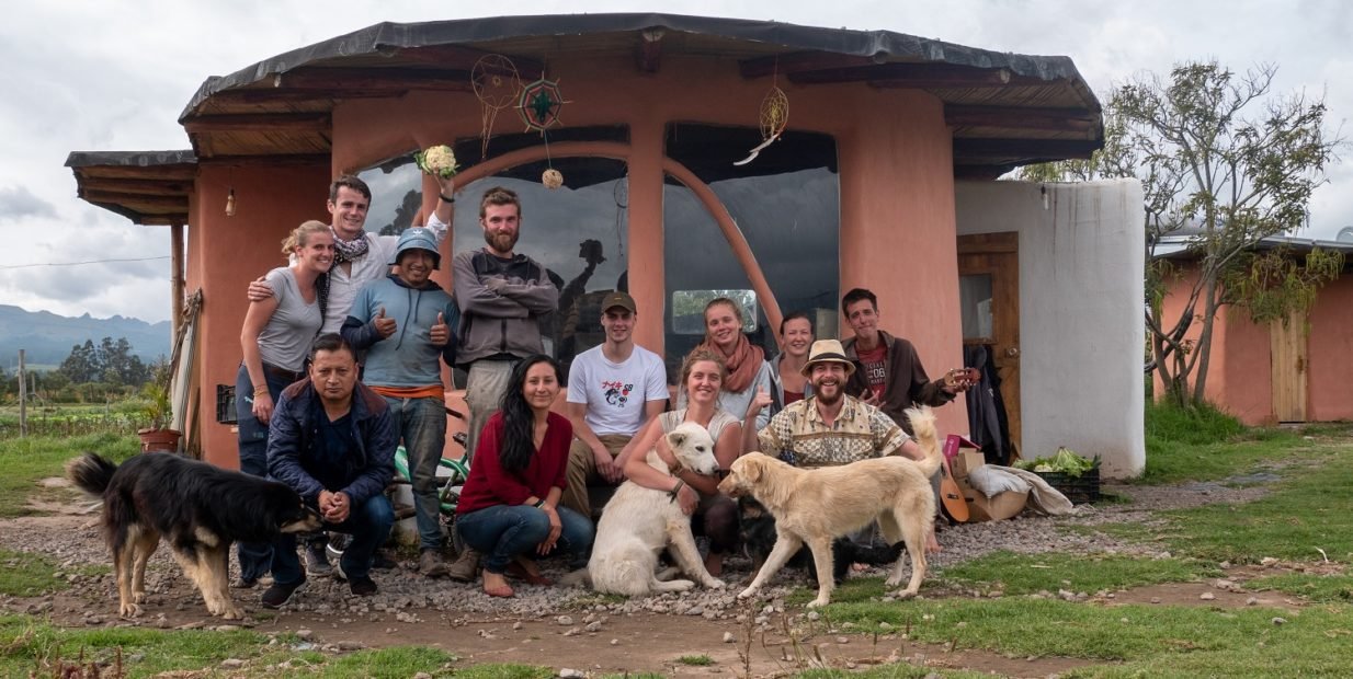 Group of international volunteers with dogs in front of an eco house at CINCA EC permaculture and organic farm near Quito, Ecuador.