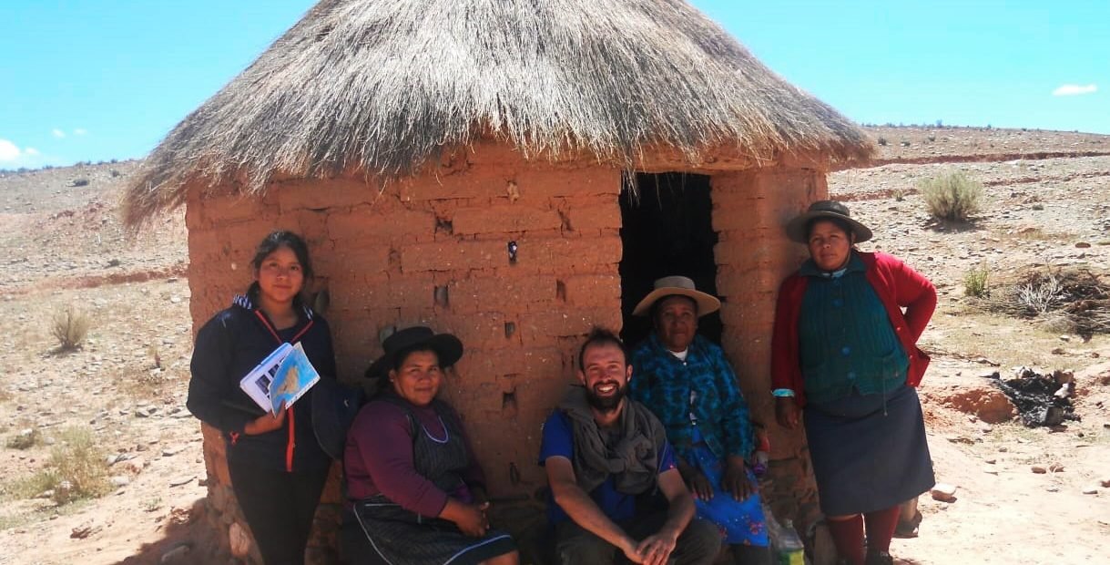Chnelik Sebastian slow traveller sitting with Indigenous women outside a small adobe hut in the Bolivian altiplano, during his long overland journey from Argentina to the Arctic Circle.