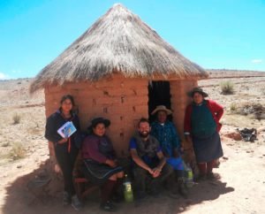 Chnelik Sebastian slow traveller sitting with Indigenous women outside a small adobe hut in the Bolivian altiplano, during his long overland journey from Argentina to the Arctic Circle.