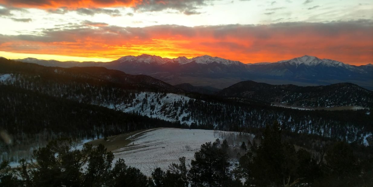 Sunset over snow-covered mountains and forest near an Earthship volunteer project in Colorado