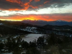 Sunset over snow-covered mountains and forest near an Earthship volunteer project in Colorado