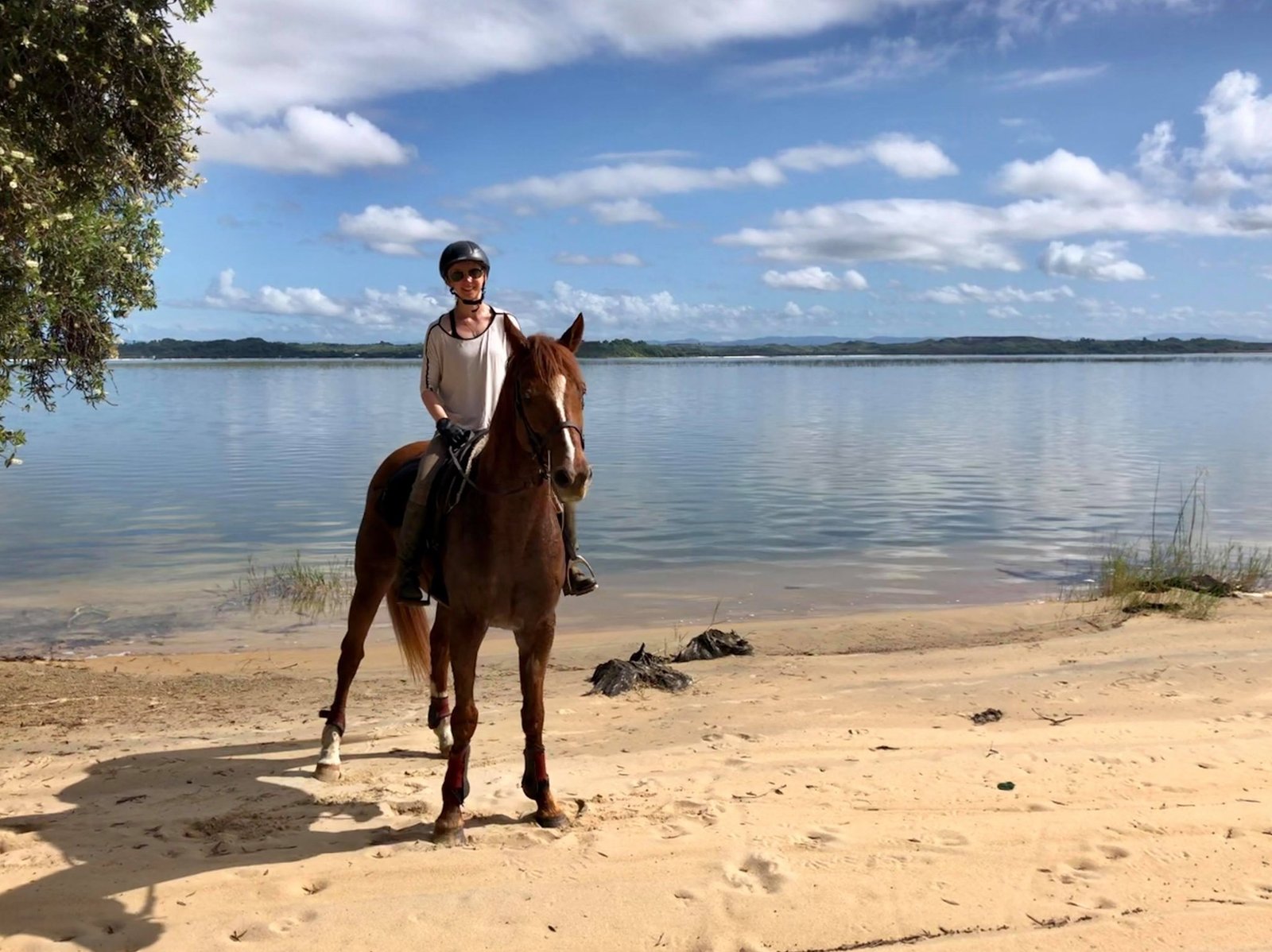 Volunteer riding a horse along a sandy lakeside beach at Faka Ranch in Madagascar