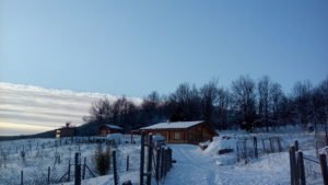 Snowy wooden house and fenced land in the Lucano Apennines, Basilicata, Italy, part of a self-sufficient volunteer project and hospitality exchange for people interested in volunteering, off grid and alternative lifestyles.
