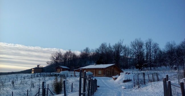 Snowy wooden house and fenced land in the Lucano Apennines, Basilicata, Italy, part of a self-sufficient volunteer project and hospitality exchange for people interested in volunteering, off grid and alternative lifestyles.