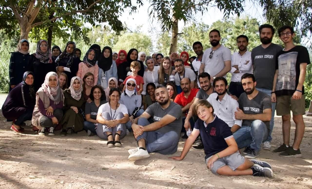 Group of SB OverSeas interns and volunteers sitting and standing outdoors during a humanitarian education programme, volunteer project and internship abroad. Volunteering, cultural exchange and community support, Voluntouring.