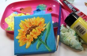 Small sunflower painting on canvas with acrylic paints and brushes, related to art volunteer projects and creative exchanges.