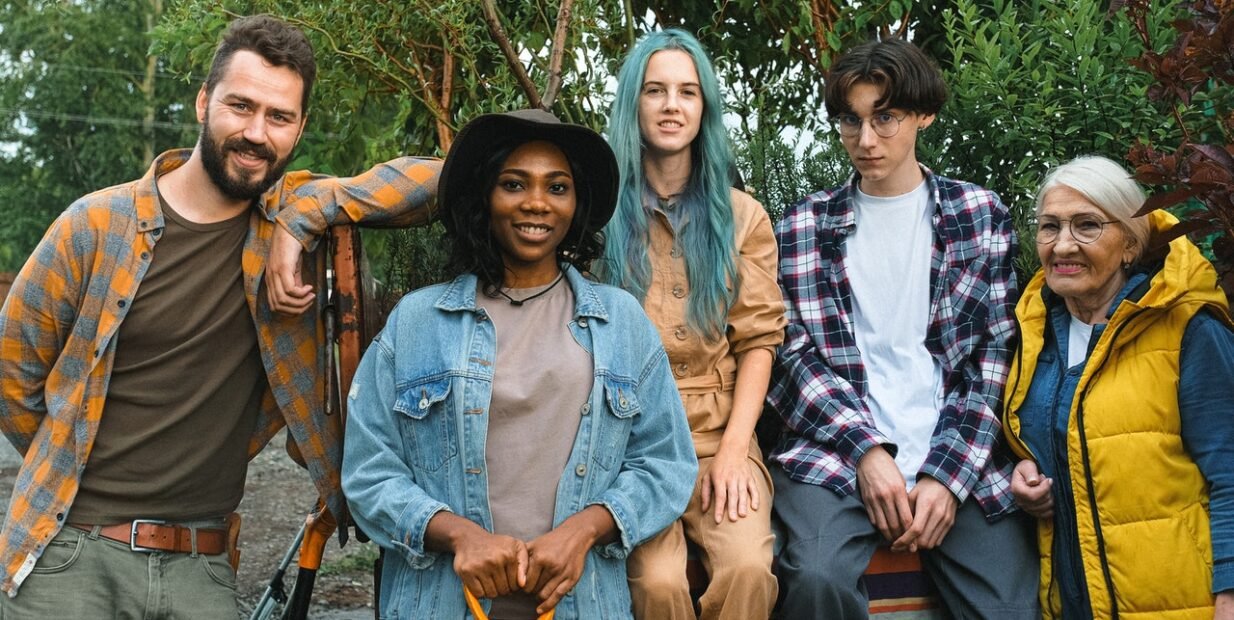 Diverse group of farm volunteers of different ages and backgrounds posing together in a garden, symbolizing community, intergenerational learning, and cultural exchange in organic farm volunteer programs.