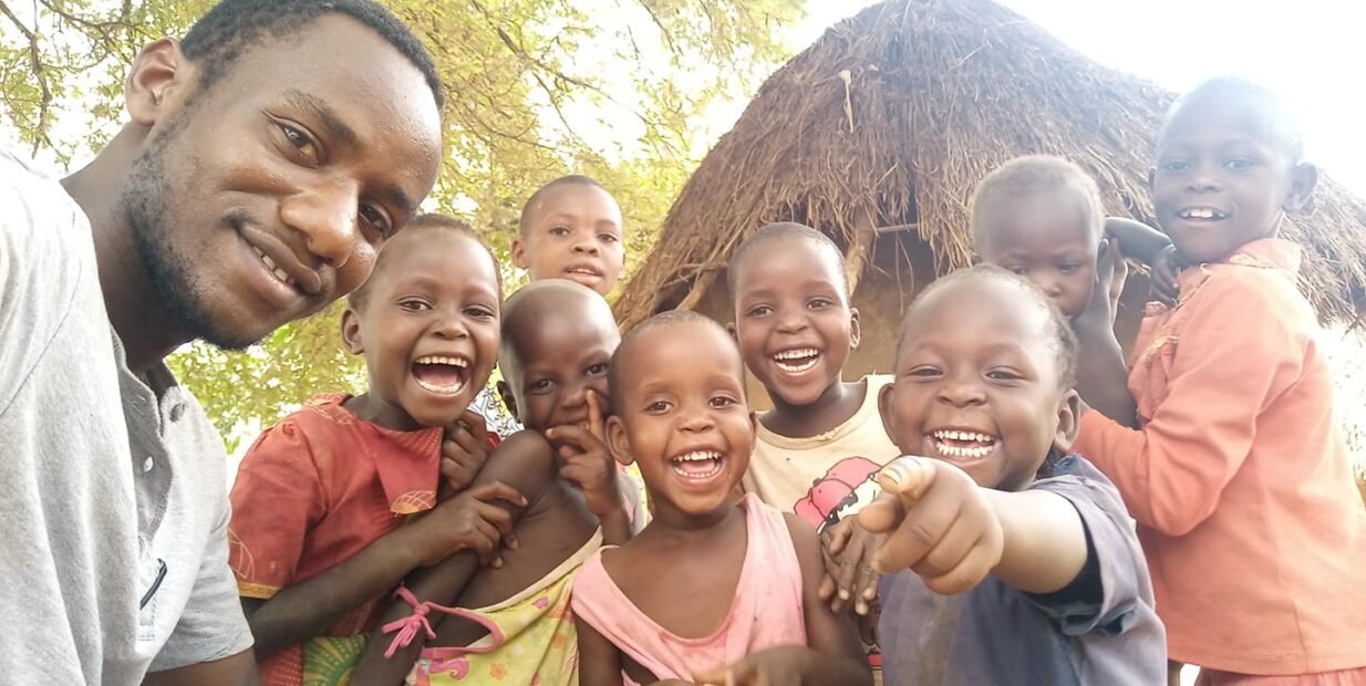 A volunteer shares a joyful moment with children in Budaka District, Uganda — part of the Organisation for Community Development Uganda’s community outreach program.