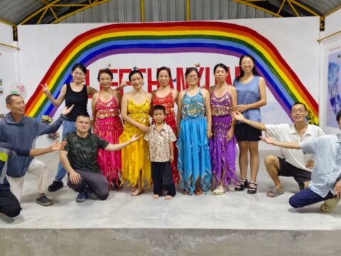 Lifechanyuan International Family Society Thailand Branch community members and volunteers standing together in front of a rainbow mural at their ecovillage.