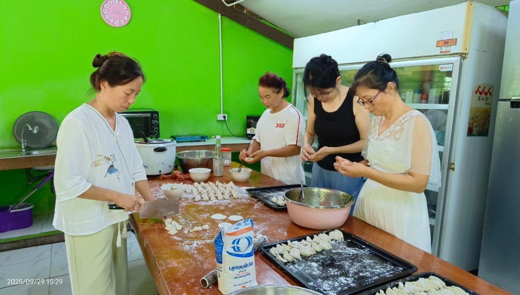 Community members preparing dumplings together in the bright green kitchen at Lifechanyuan ecovillage in northern Thailand.