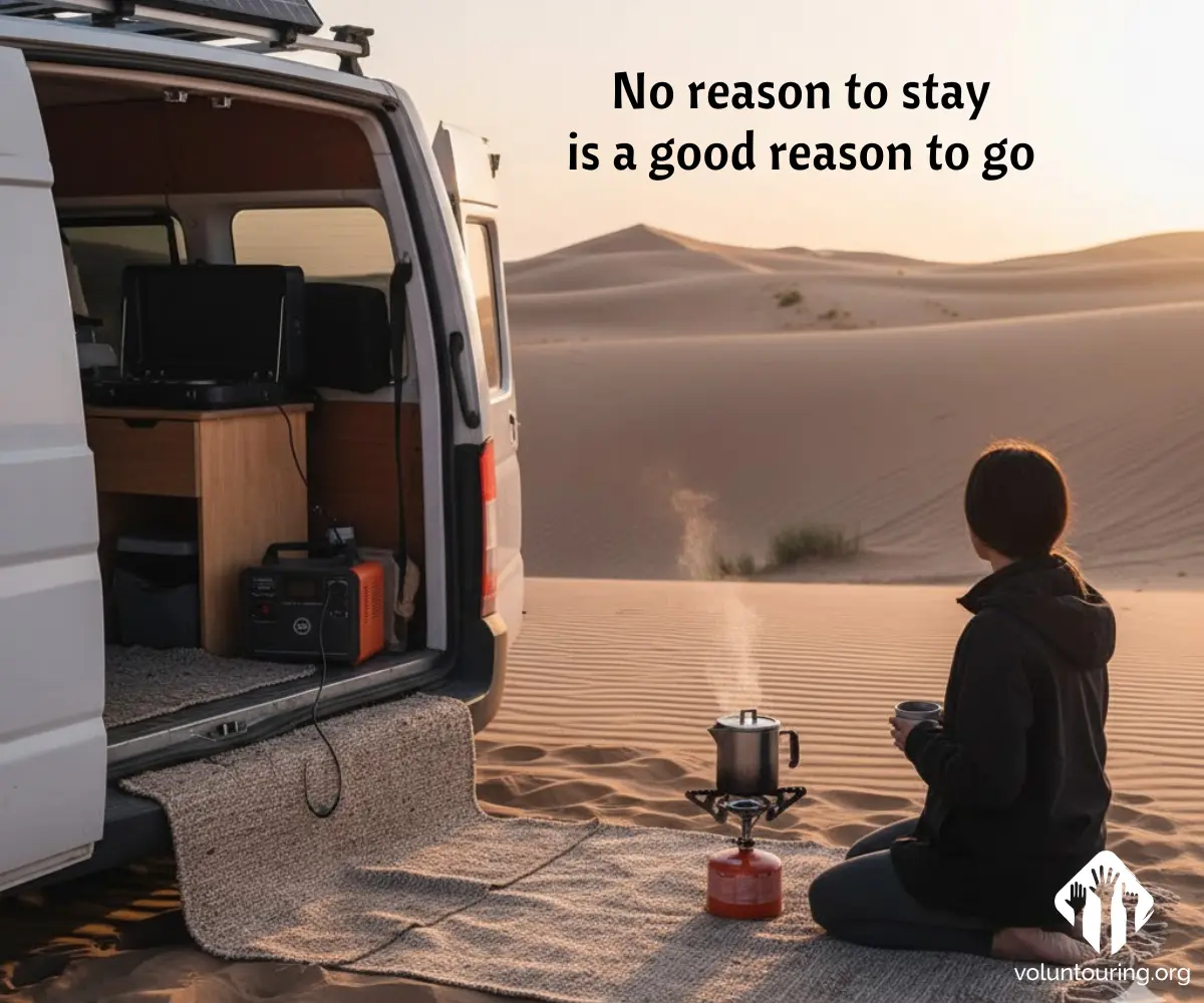 Camper van parked on desert sand at sunrise, woman sitting on a rug with a mug beside a small camping stove. Quote reads, “No reason to stay is a good reason to go.”