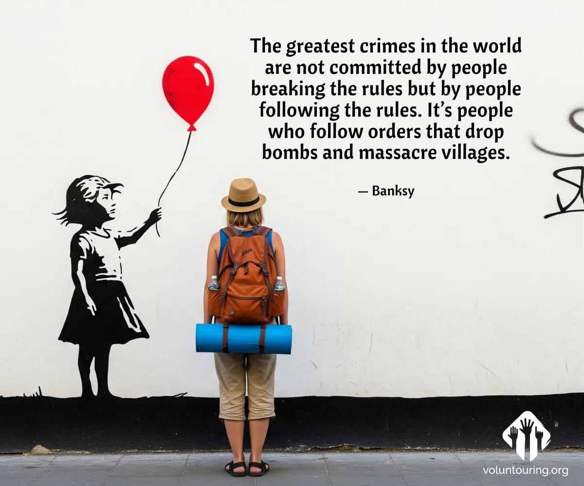 Backpacker woman with hat and travel gear standing in front of Banksy’s Girl with Balloon mural and anti-war quote on white wall