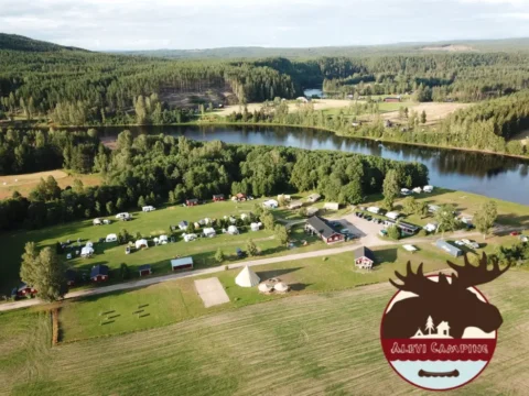 Aerial view of Alevi Camping in Värmland, Sweden, showing cabins, tents, and green forest landscape by the river — summer volunteer opportunity with free accommodation.