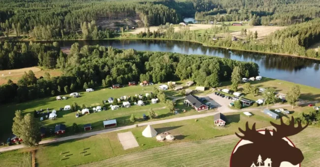 Aerial view of Alevi Camping in Värmland, Sweden, showing cabins, tents, and green forest landscape by the river — summer volunteer opportunity with free accommodation.