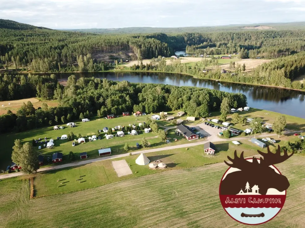Aerial view of Alevi Camping in Värmland, Sweden, showing cabins, tents, and green forest landscape by the river — summer volunteer opportunity with free accommodation.