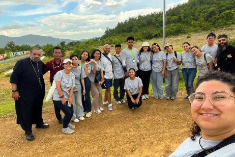 Smiling volunteer taking a selfie with a diverse group of AHHA Education team members and volunteers outdoors in Kampot, Cambodia. 