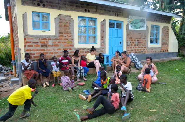 Volunteers and children outside Green Village Hope Children Home, brick house with blue door in Ipali, Vihiga County, Kenya.