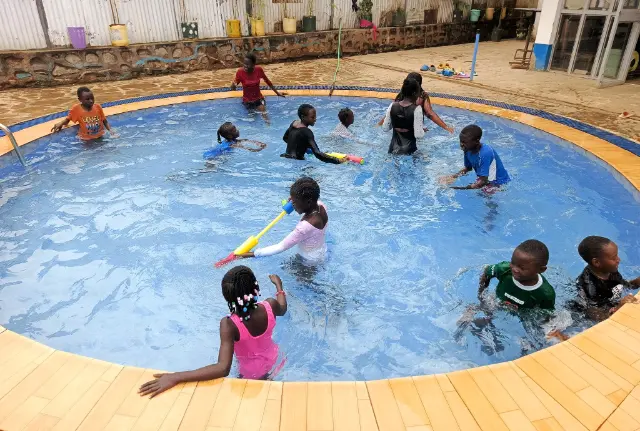 Children at Green Village Hope Children Home in Vihiga, Kenya, enjoying a safe swimming lesson in a round pool with float toys.