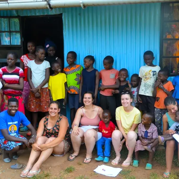 Volunteers with children at Green Village Hope Children Home in Vihiga, Kenya, group photo outside a blue classroom wall.