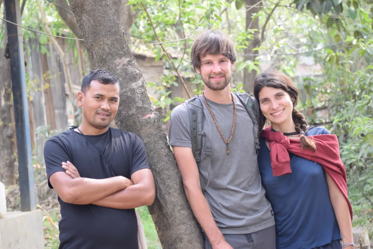 Volunteer in Manipur India at Langon Sanglen: host with two international volunteers smiling outdoors beside a tree near Imphal.