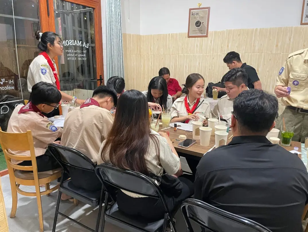Vietnamese teens in uniform attending an evening English and culture workshop in Dong Nai, Vietnam, seated around a table with notebooks and drinks, part of the “Teach English in Dong Nai, Vietnam” volunteer homestay.