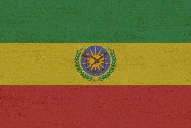 Ethiopian flag with green, yellow and red horizontal stripes and a blue disc with a yellow star emblem in the center.