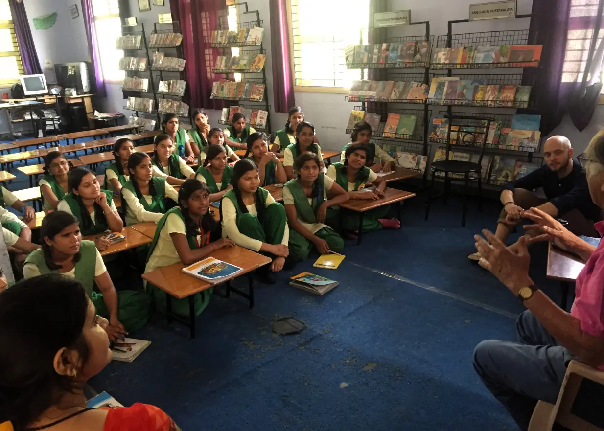 Girls at a rural India girls’ school in Uttar Pradesh listening to a lesson in the library with volunteer teachers