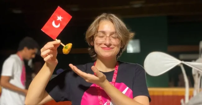 Smiling ESC volunteer holding a small Turkish flag and local food at an English immersion youth camp in Siirt, part of ESC volunteering in Turkey with CEDID Association.