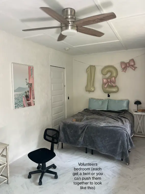 Shared twin bedroom for women volunteer accommodation in Volcano, Hawaii, showing simple beds, desk and fan in rainforest B&B work exchange.