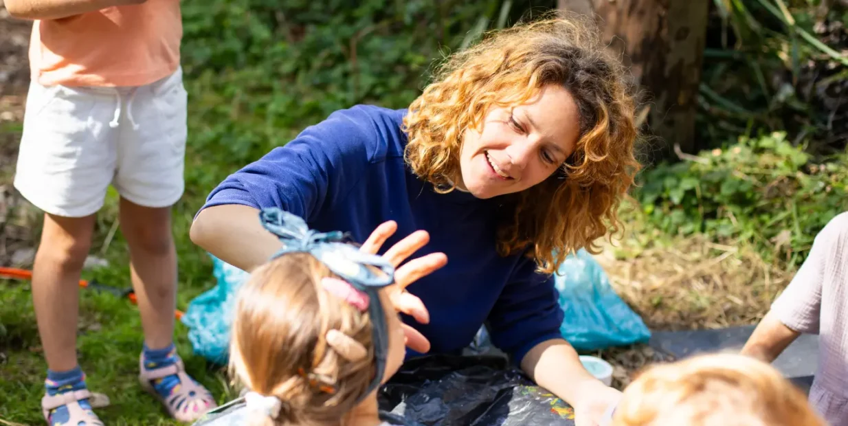 Camp staff member engaging with children during an outdoor activity at a nature camp in Amsterdam, Netherlands.