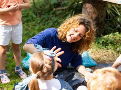 Camp staff member engaging with children during an outdoor activity at a nature camp in Amsterdam, Netherlands.