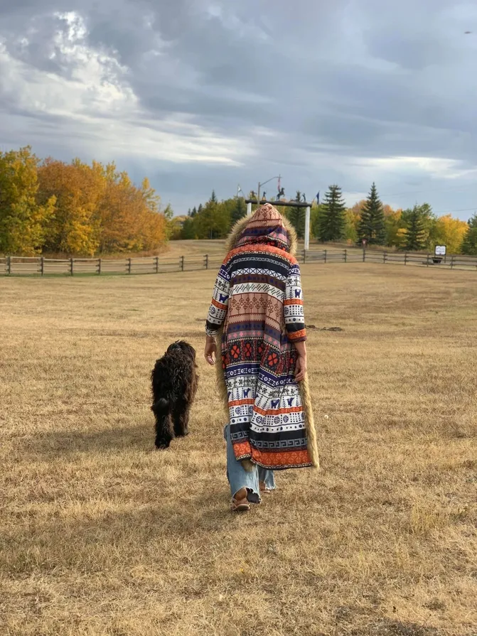 Woman walking with a Briard therapy dog across an open field near Calgary, Alberta, Canada, part of the Sanctuary on Wheels volunteer project with trained dogs.