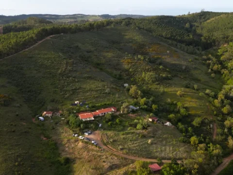 Aerial view of Luna Solua off grid family farm in Alentejo, Portugal, surrounded by forested hills, rural tracks, gardens and open land where volunteers help with natural building, gardening and rural life projects.