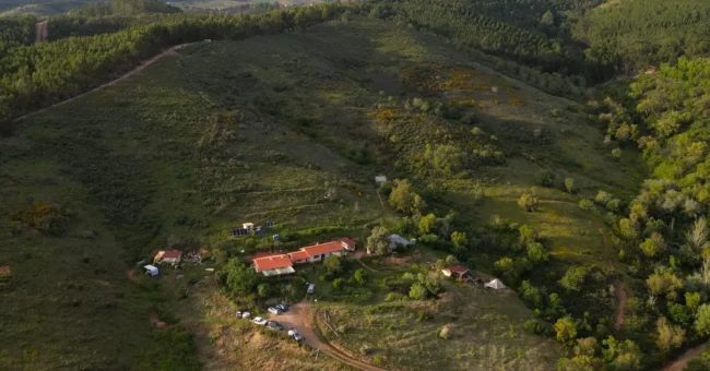 Aerial view of Luna Solua off grid family farm in Alentejo, Portugal, surrounded by forested hills, rural tracks, gardens and open land where volunteers help with natural building, gardening and rural life projects.