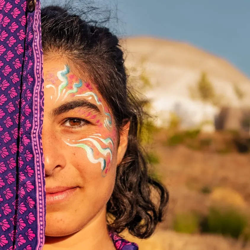 Volunteer with face paint at an Algarve eco retreat in Portugal, with a retreat dome in the background at a reforestation and land restoration project.