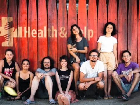 Group of Health & Help staff and volunteers sitting outside a rural healthcare clinic in Guatemala, for a medical volunteer Guatemala opportunity supporting community health.
