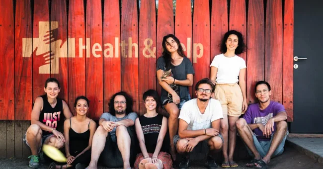 Group of Health & Help staff and volunteers sitting outside a rural healthcare clinic in Guatemala, for a medical volunteer Guatemala opportunity supporting community health.
