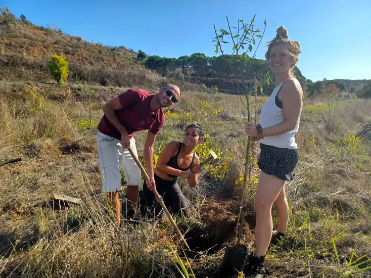Volunteers planting a tree in the Algarve countryside at a reforestation and land rehabilitation project near Monchique, Portugal.