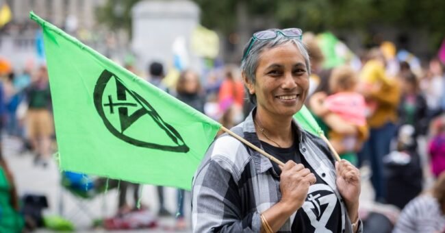 Climate activist holding an Extinction Rebellion flag during an XR protest.