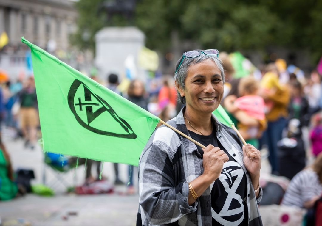 Climate activist holding an Extinction Rebellion flag during an XR protest.