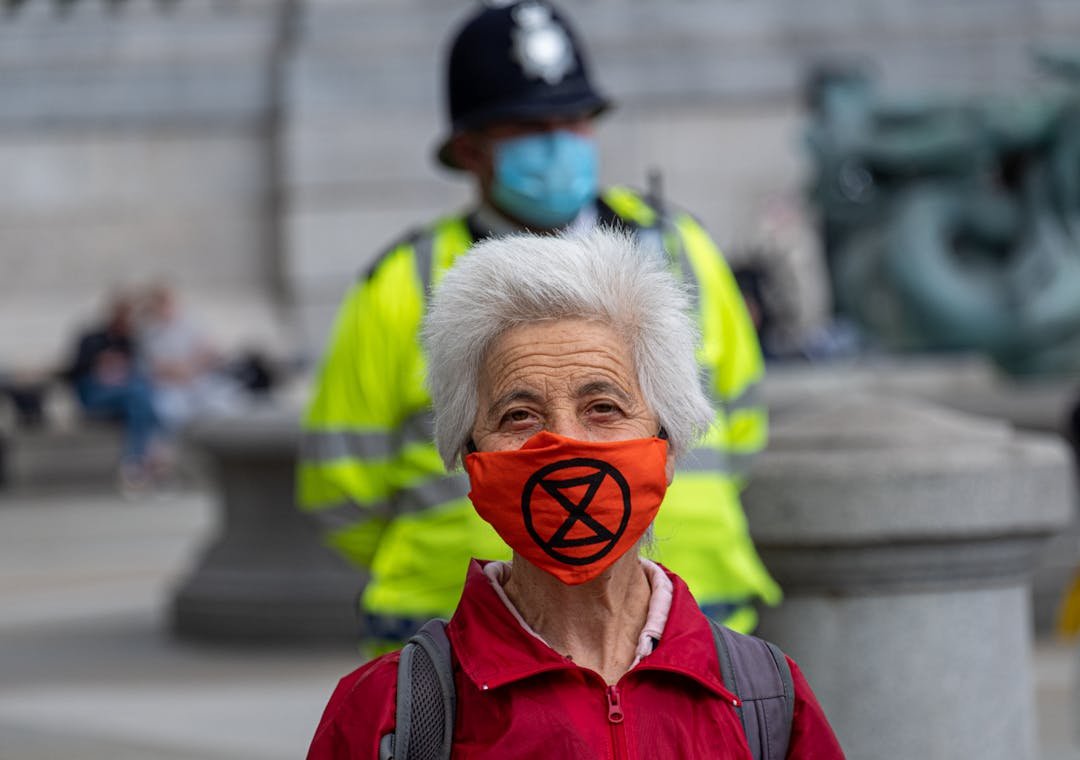Older climate activist wearing an Extinction Rebellion face mask during an XR protest.